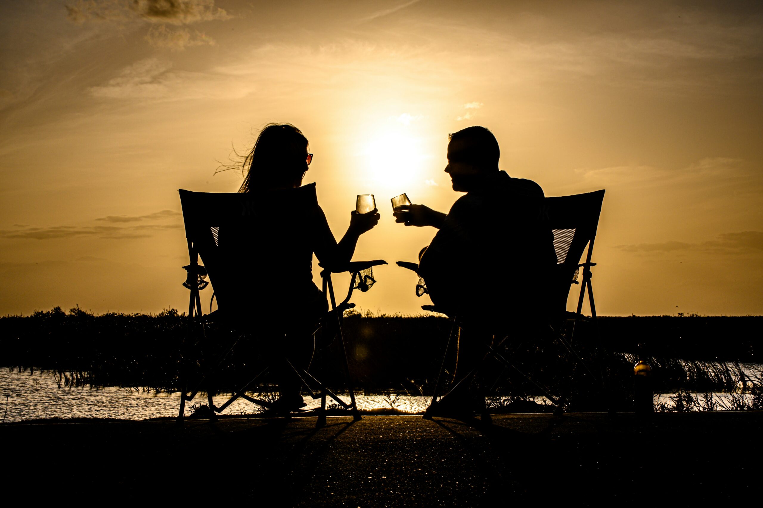 a man and woman sitting on a chair at the beach